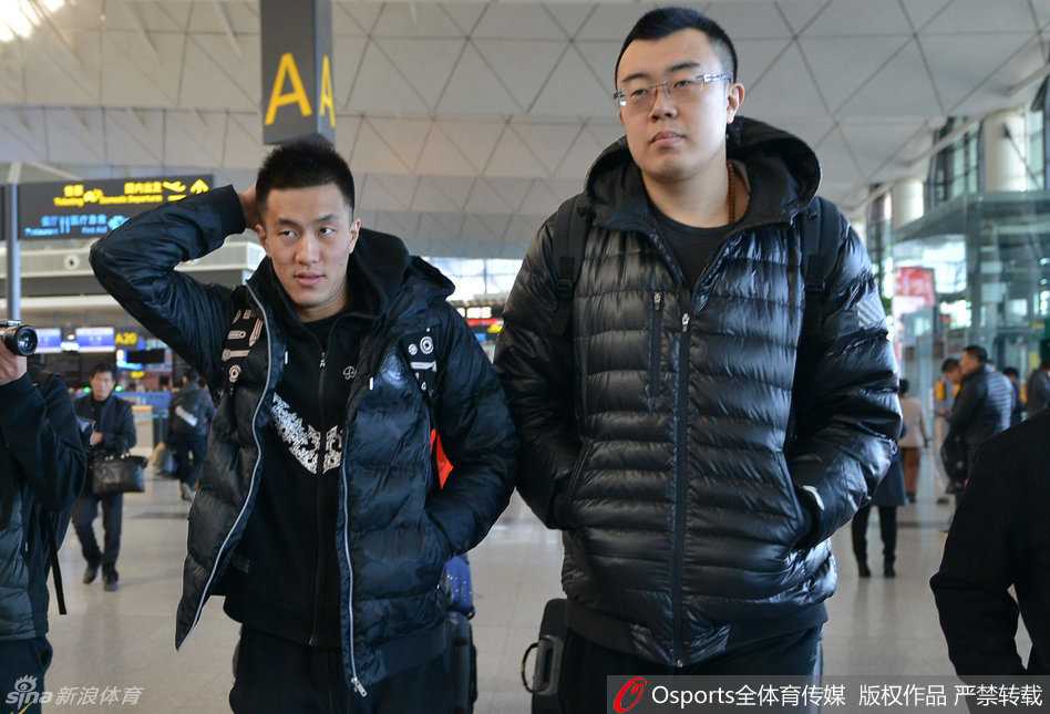 辽宁男篮主教练郭士强指导在机场被热情的球迷团团围住，他面带微笑，正俯身为球迷手中的纪念品签下名字，尽显儒帅风范。