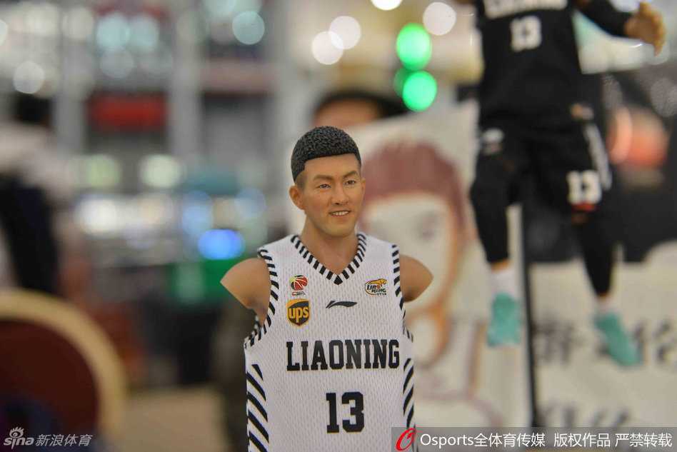 展台玻璃柜内，郭艾伦的人偶被精心摆出运球突破的姿势，身披白色主场球衣，神态专注，一旁陈列着他穿过的同款球鞋，引来观众隔着玻璃仔细端详。