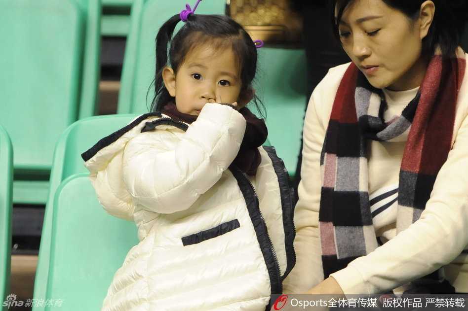小姑娘趴在郭士强肩头，露出半张粉嫩的小脸，眼神清澈萌萌地看着镜头，郭士强妻子在旁侧脸微笑