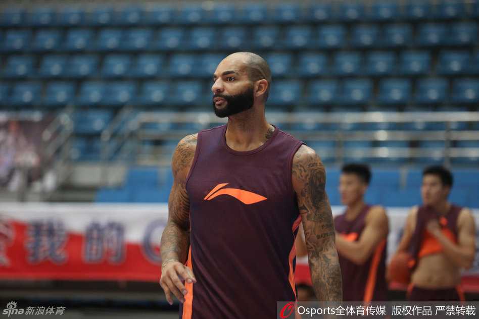 易建联在进行赛前拉伸，高大的身躯在拉伸时展现出惊人的柔韧性，背后是无数次枯燥训练积累的成果。