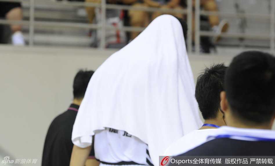 韩德君坐在场边的替补席上，依然无法接受进一步的治疗，队医蹲在地上持续为他进行紧急止血处理，韩德君的表情依旧痛苦，眼神中却透露出不甘与坚毅。