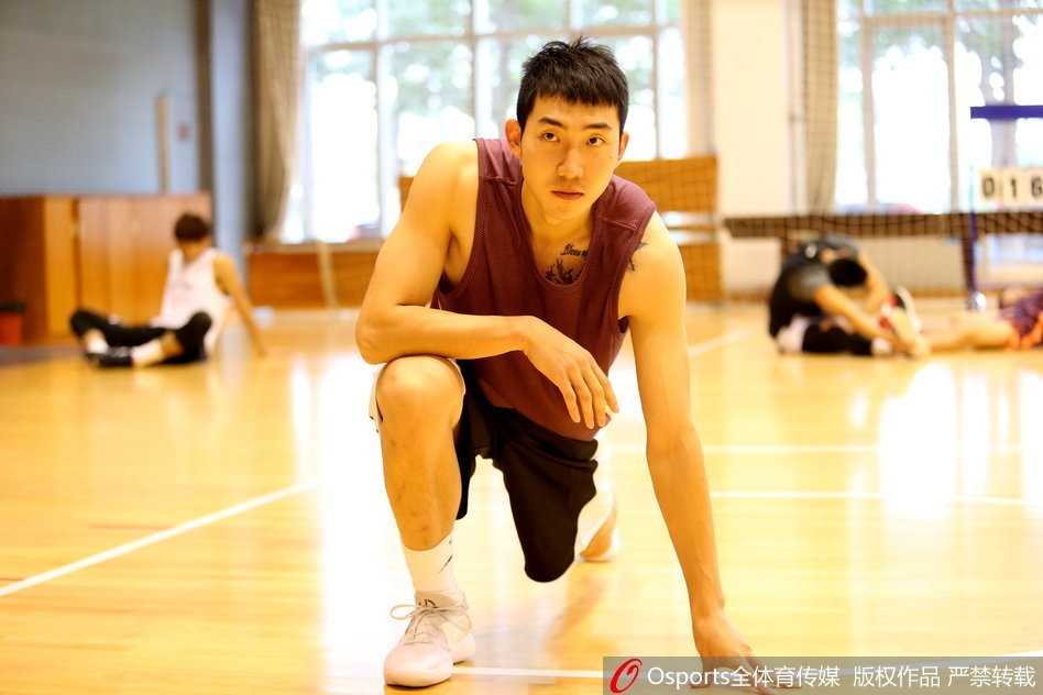 在卧推测试区，一名身穿白色训练服的球员正全力向上推举杠铃，手臂青筋暴起，旁边的保护人员全神贯注，时刻准备提供帮助。