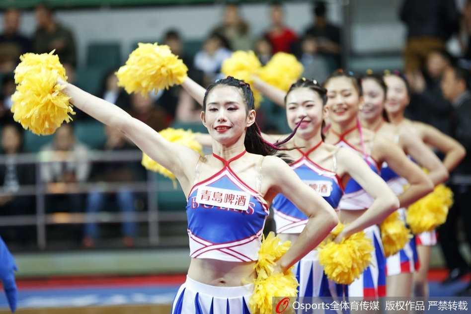 特写镜头捕捉到了一位篮球宝贝自信的微笑，她手中的花球随着欢快的节奏上下翻飞，飞扬的发丝和明亮的眼神传递出属于青春特有的朝气与活力。