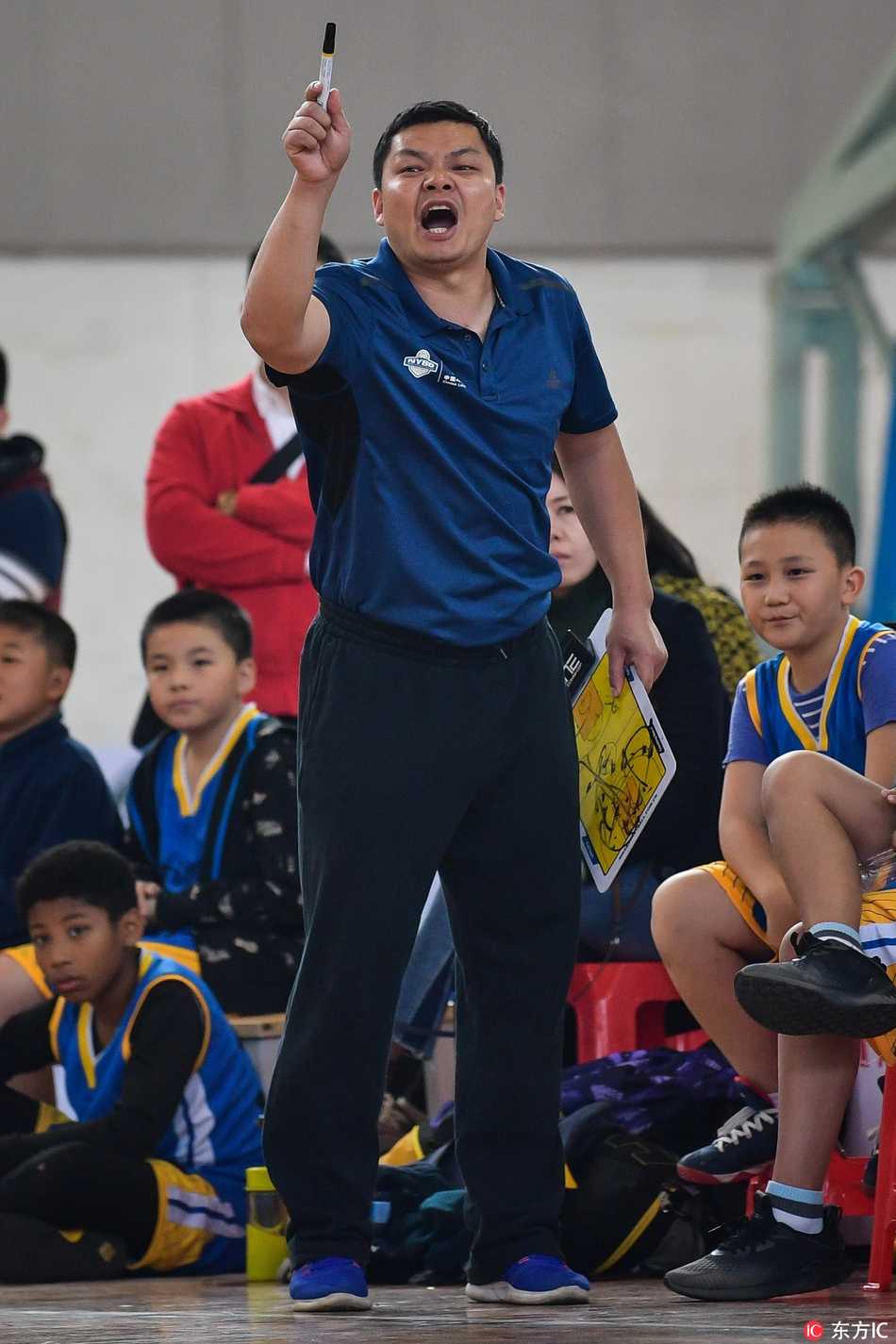 U12教练在场边挥舞着拳头，表情既紧张又充满期待，双眼紧紧盯着场内，仿佛要将自己的力量通过呐喊传递给每一位小队员。