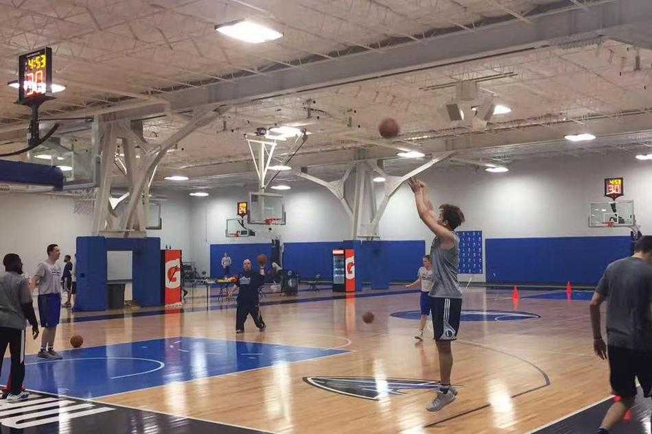 丁彦雨航双手抱球置于腰间，身穿白色小牛队训练背心，在训练馆的蓝色背景板前留下定妆照，眼神坚定地望向前方