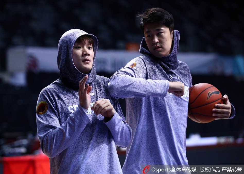 助理教练正在为内线球员莫泰尤纳斯单独讲解防守站位，莫泰表情严肃，认真聆听并比划着防守动作。