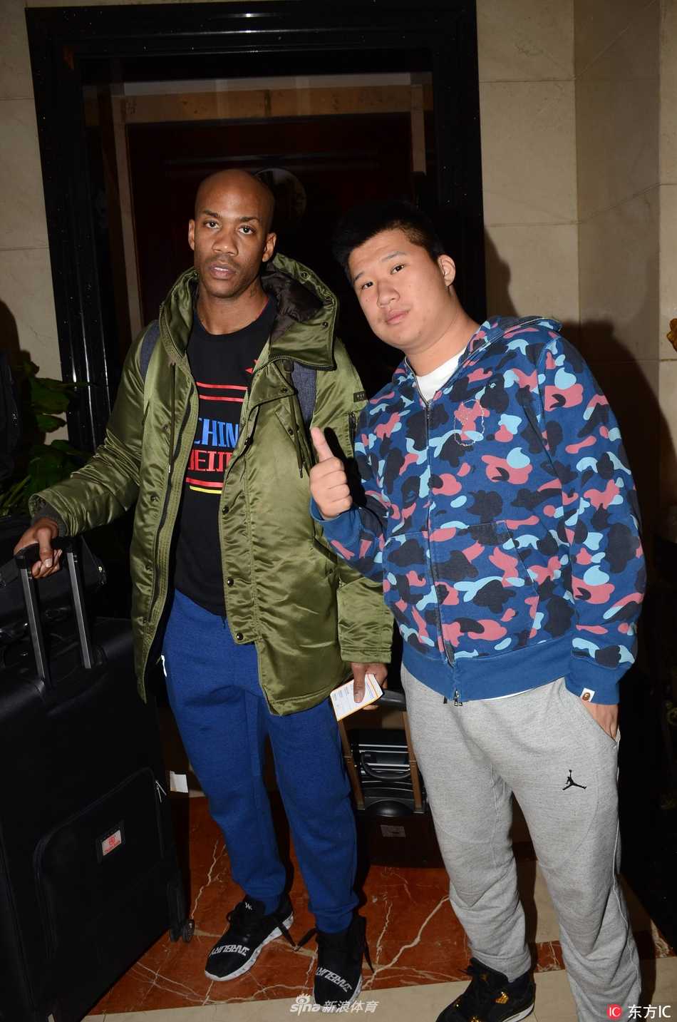 酒店大堂内，马布里微微弯腰侧耳，认真倾听一位小球迷的话语，身后的北控队友杨敬敏等人注视着这暖心一幕，光洁的地板映照着他们融洽的身影。