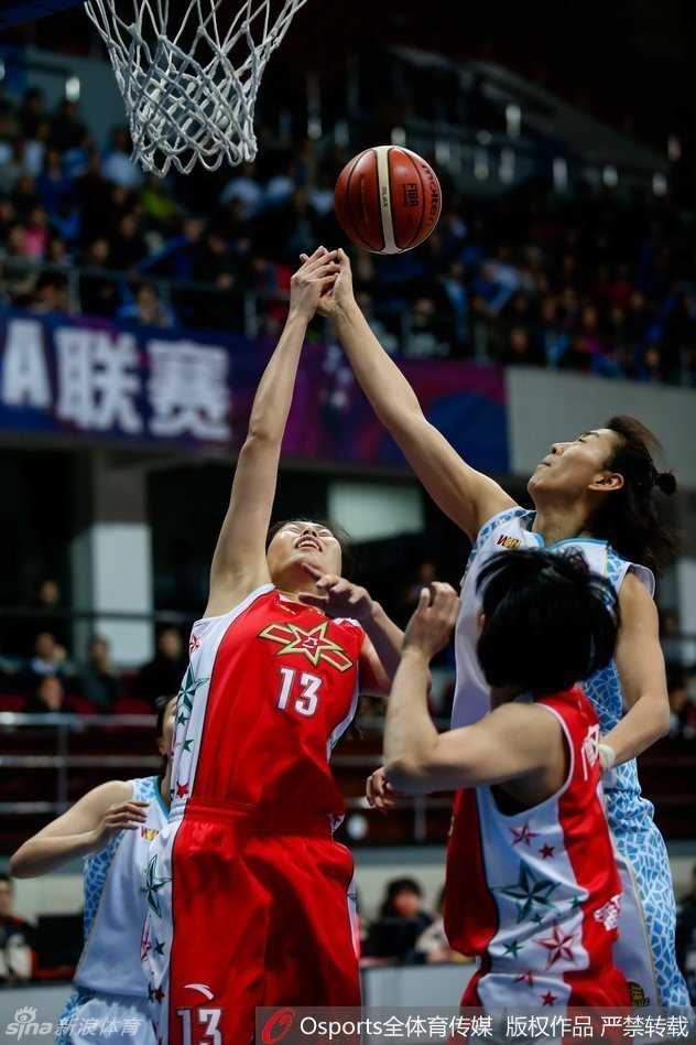 北京女篮球员在混战中高高跃起，以一记漂亮的挑篮终结进攻，篮下的拼抢激烈异常。