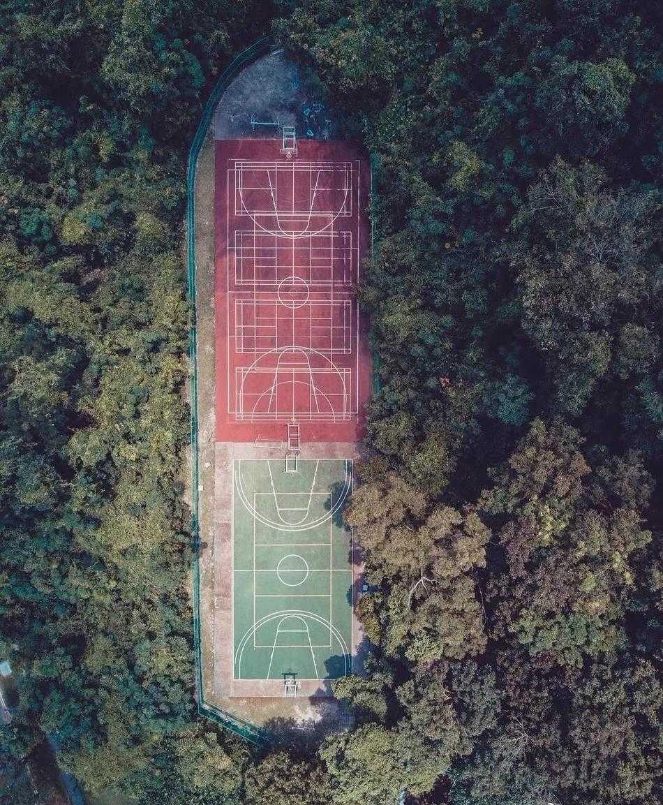 雨后，篮球场低洼处积水如镜，倒映出天空的晚霞和静止的篮架，现实与倒影虚实莫辨，营造出超现实的静谧美感。