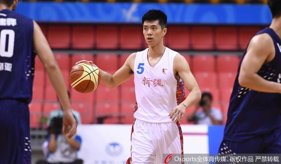 新疆队球员阿不都沙拉木在篮下以一敌三，高高跃起，眼神坚毅地将球送入篮筐