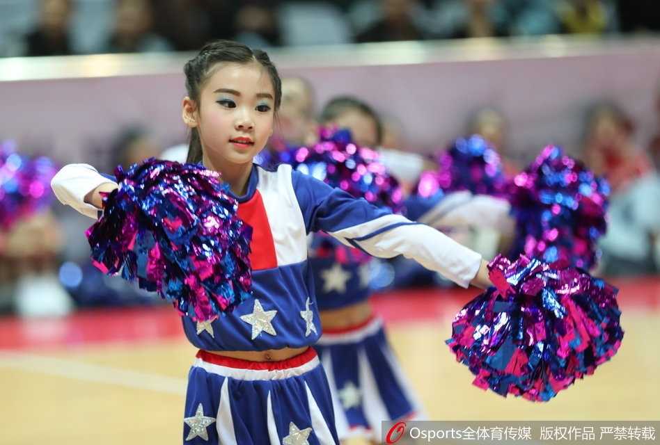 两个小宝贝在休息间隙紧紧抱在一起，脸上带着天真的笑容，身后的赛场大屏幕映衬出她们欢快的身影