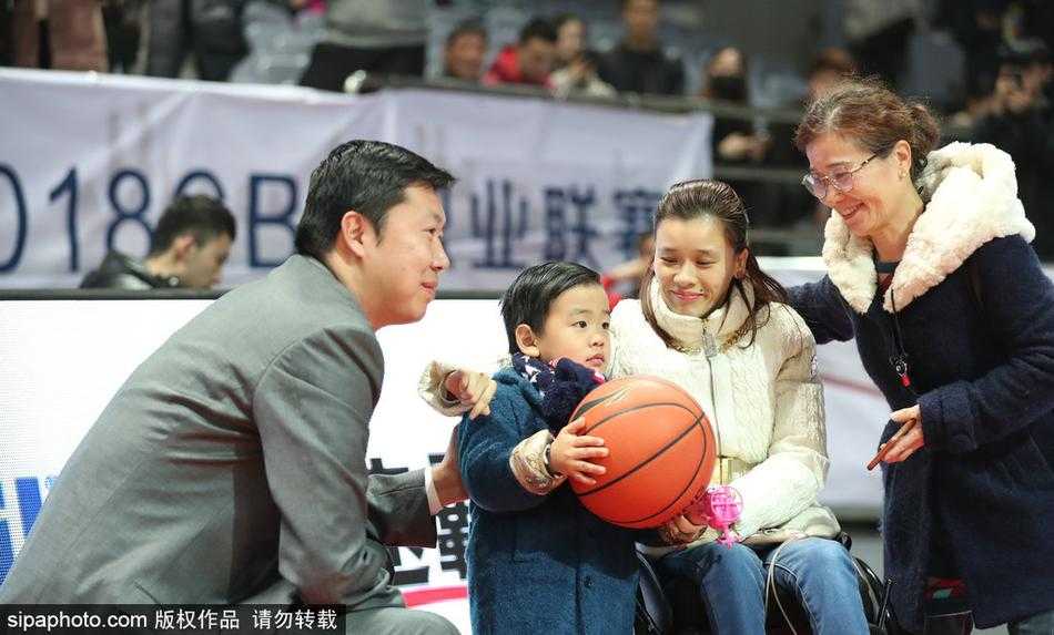 桑兰与丈夫黄健并肩坐在看台上，黄健神情专注地望向球场，桑兰则低头与怀中的儿子亲昵互动，一家三口其乐融融。