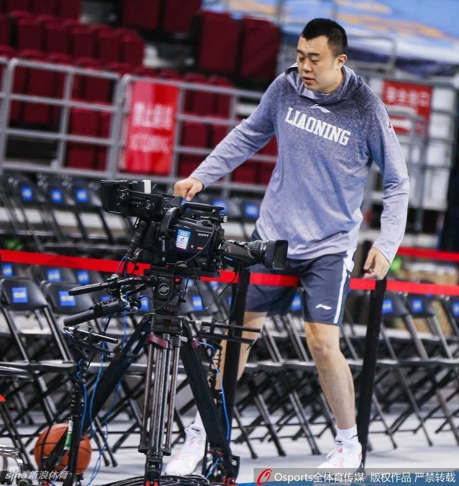 身披辽宁队训练服的韩德君，张开双臂，大步流星地准备跨越场边的广告牌，动作既认真又透着几分滑稽，引得场边工作人员侧目。