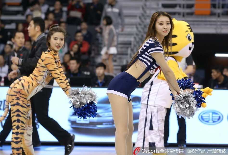 全景视角下，六位篮球宝贝摆出虎踞造型的结束 pose，她们错落有致地分布在球场中央，橙色的服装在深蓝色的地板上格外醒目，宛如盛开在赛场上的烈焰之花