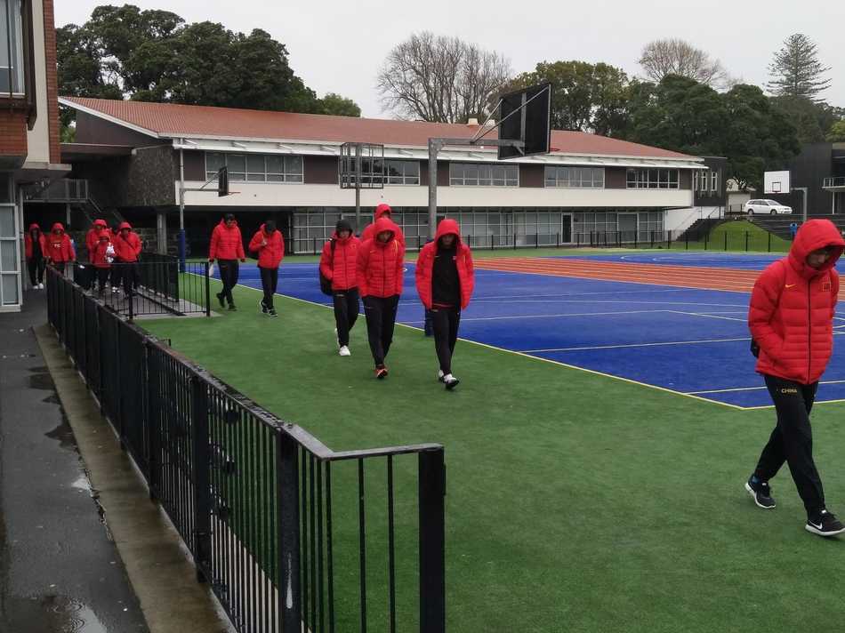湿冷的空气中，身穿长款黑色棉服的男篮队员们在场边集结，呼出的白气与专注的眼神，构成了冬日训练场上最火热的画面。