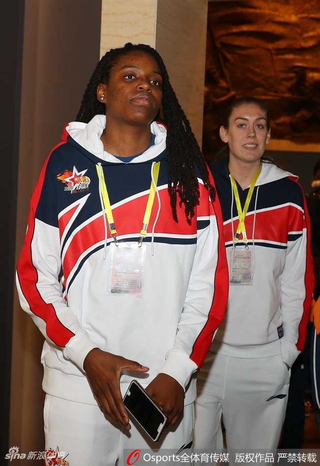 孙梦然侧身低头，温柔地看向身边的小朋友，她胸前的八一队徽与纪念馆的红色主题交相辉映。