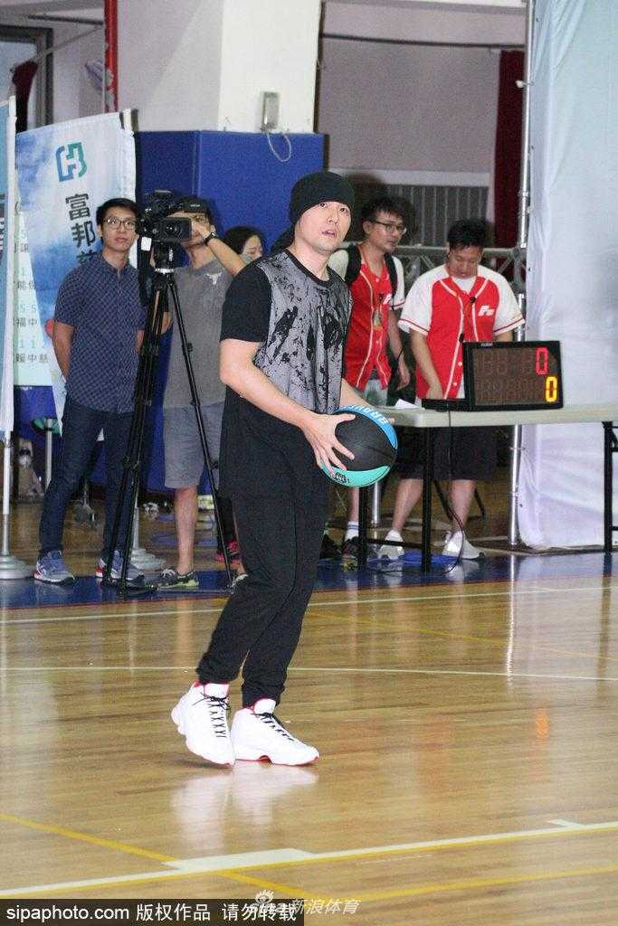 活动互动环节，周杰伦半蹲着身子与一位小球员击掌，他脸上挂着亲切的笑容，头巾下的眼神温柔而鼓励，传递出满满的爱心与正能量。