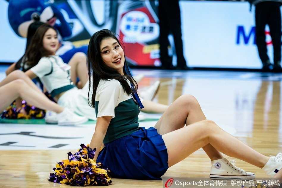 三名篮球宝贝背对镜头排成一列，双手高举，身材曲线一览无余，她们身后的观众席虚化成一片人海，整个体育馆的气氛因为她们的带动而沸腾。