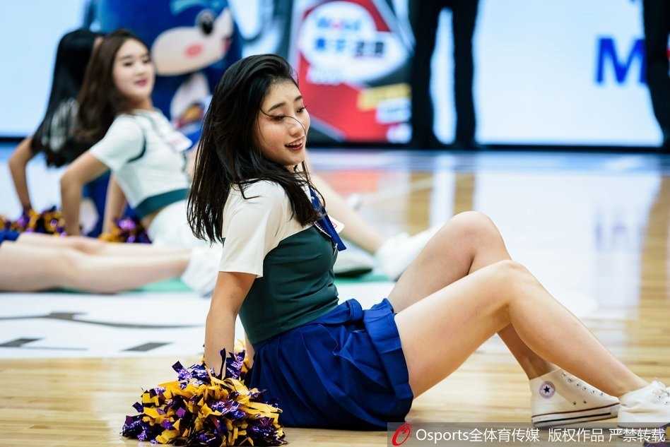 这位宝贝侧身回眸，长发如瀑般洒下，她伸出手指指向观众席，仿佛在与每一位看台上的球迷进行互动，邀请大家一同加入这场篮球狂欢。