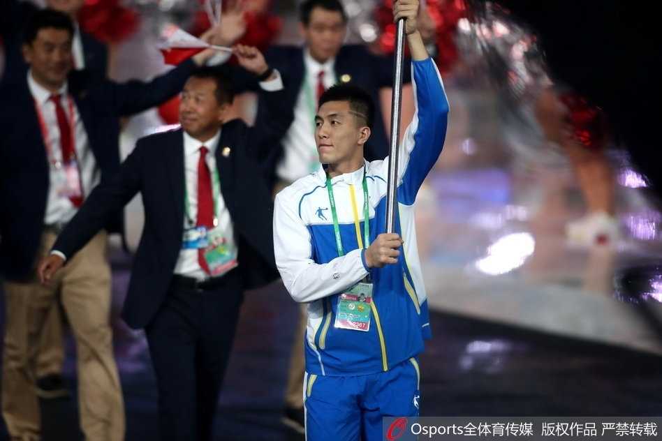 聚光灯下的郭艾伦，身姿挺拔，面带微笑，挥舞旗帜的动作潇洒而有力。