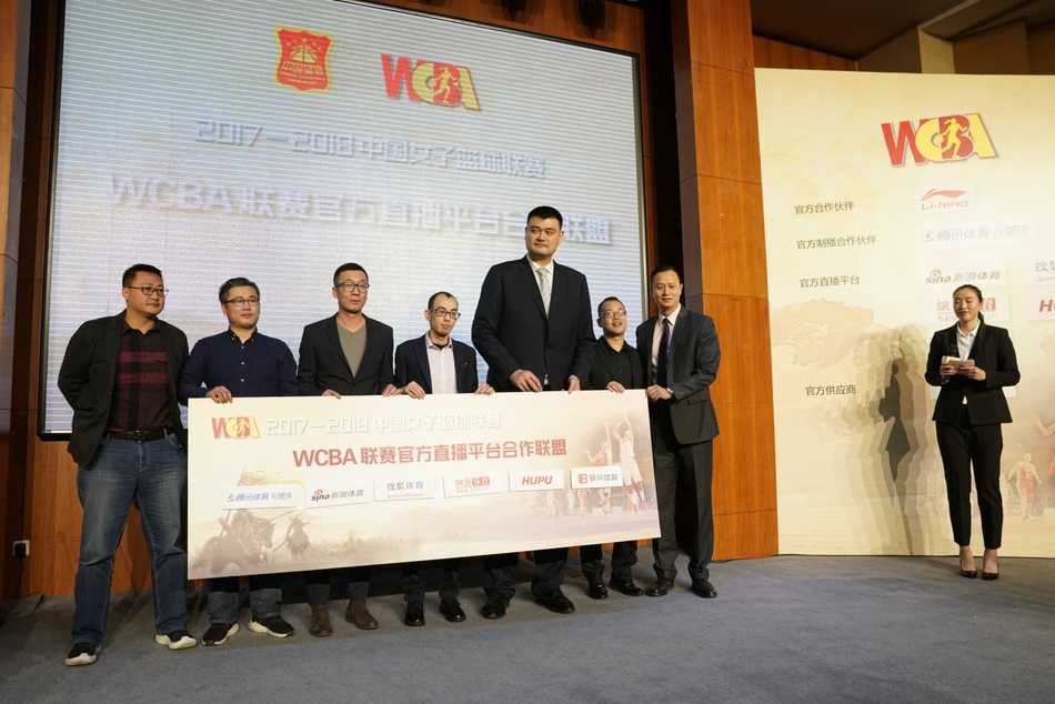 篮球巨人姚明在发布会台上凝神倾听，眼神中流露出对中国女篮未来的深切关怀与坚定信心。