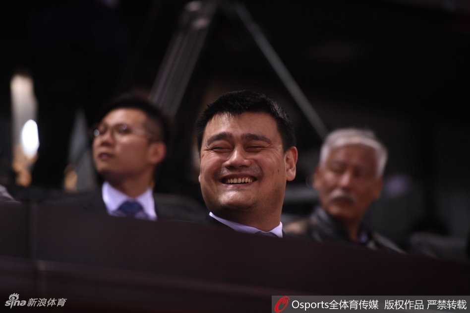 姚明双手抱在胸前，脸上挂着无奈又好笑的表情，眼睛睁得圆圆的，似乎在为场上球员投出的离谱三线球感到不可思议。