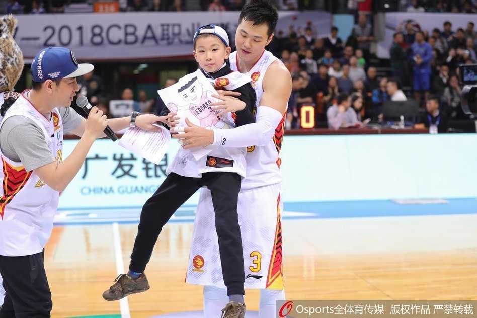 深圳大运中心体育馆内灯火辉煌，身穿白色球衣的深圳队球员们正在热身，背景是醒目的CBA联赛标志，全场球迷的目光都聚焦在这场特殊的赛事上。