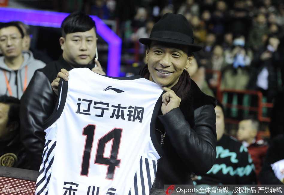 场边的宋小宝神情专注地与身边好友低头耳语，眉宇间透着对比赛的投入与热爱，不时露出标志性的狡黠笑容。