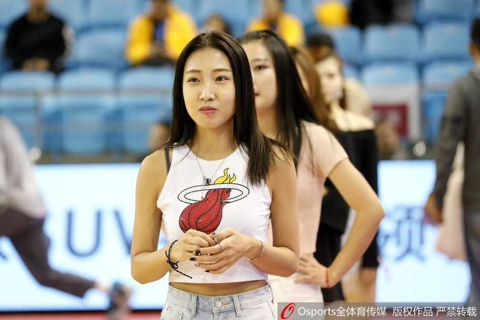 特写镜头下，一位领舞的篮球宝贝笑容灿烂如花，双手指向看台与观众热情互动，在赛场灯光照耀下，健康的肤色与精致的妆容显得格外迷人。