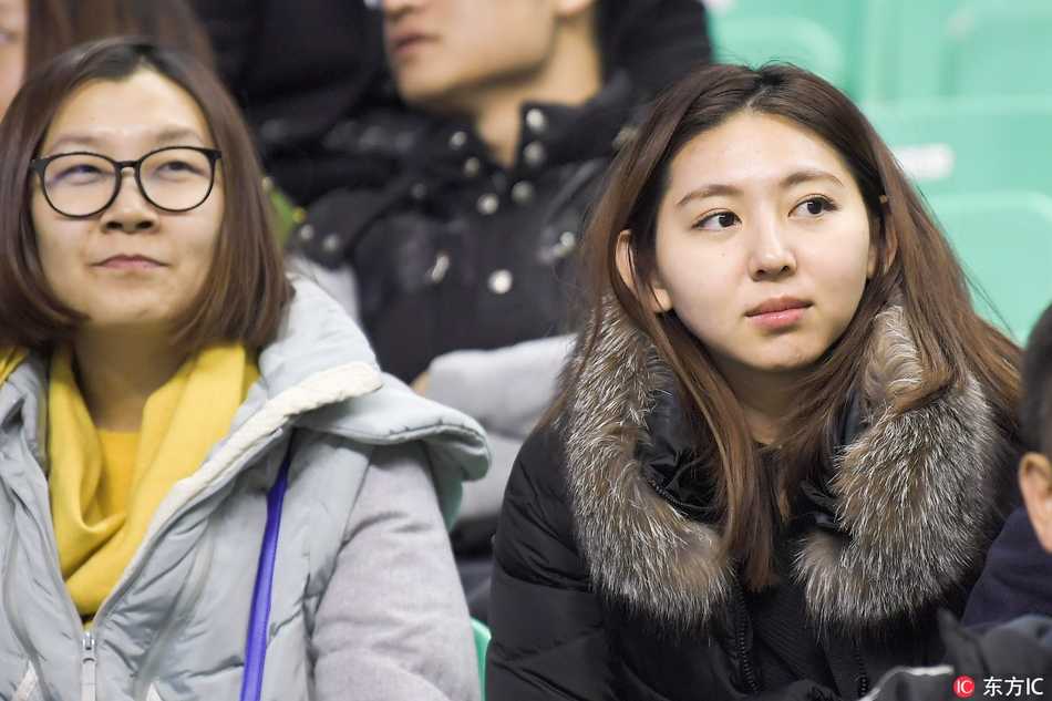 一位戴着圆框眼镜的文艺女球迷，在喧闹的看台上托腮凝望赛场，眼神中充满了对偶像的期待与专注。