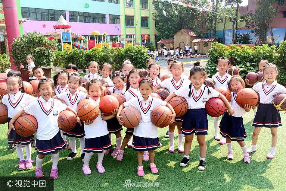 数百名幼儿身着统一园服，在绿茵操场上整齐列队，手中的橙色篮球仿佛跳跃的精灵，场面蔚为壮观
