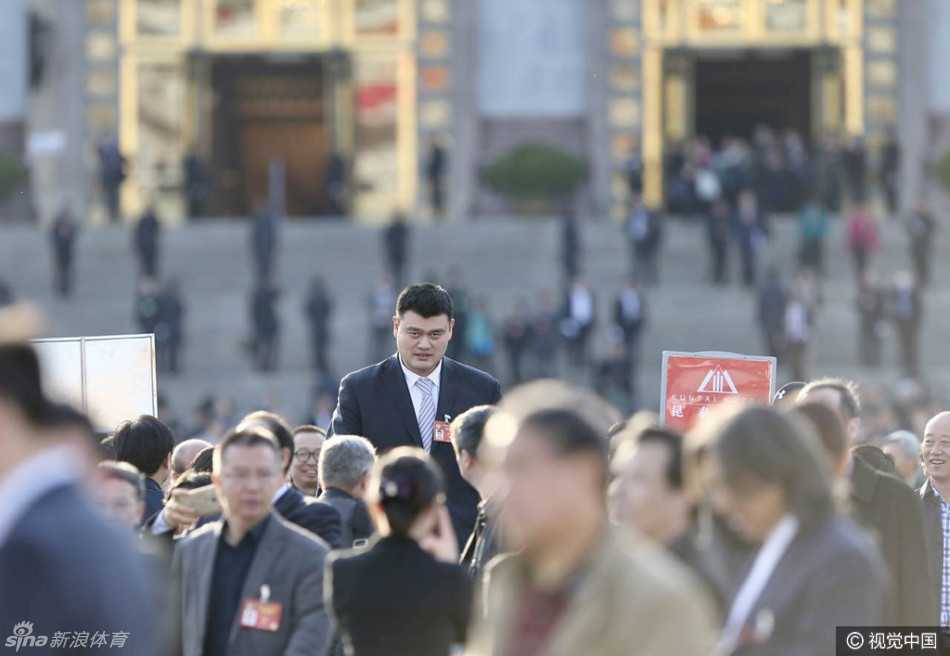 走出会议中心的姚明步履沉稳，身旁的与会人员在他高大的身形映衬下显得格外娇小，他目光平视前方，若有所思