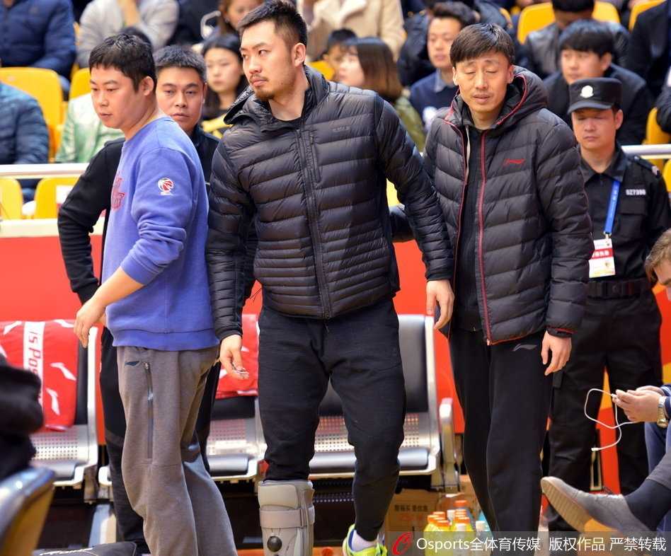 从高处俯瞰，睢冉独自一人坐在空荡的替补席区域，地板上散落着毛巾和球员物品，他左脚上的白色护具在一片深色座位中格外抢眼，整个场景充满孤寂感。