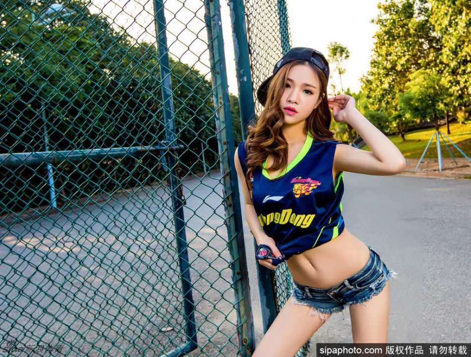 篮球宝贝身穿白色热裤，侧身回眸，长发随风飘动，修长的双腿在阳光下显得格外耀眼，青春气息扑面而来。