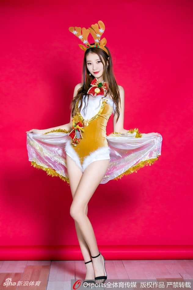 黄逸辉在圣诞背景板前摆出俏皮手势，嘟嘴卖萌的表情显得活力十足，粉色系的着装让她看起来就像是从童话中走出的节日精灵