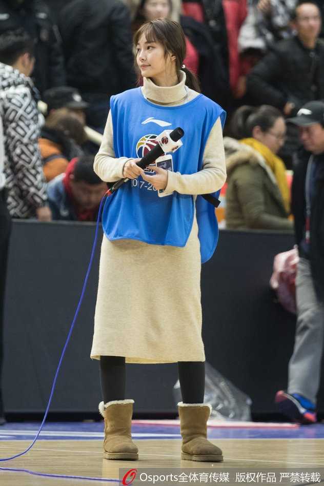 镜头拉近，美女主持轻倚场边广告板，一头秀发自然垂落，眼神清澈而坚定，仿佛正用无声的语言为广厦队加油打气。