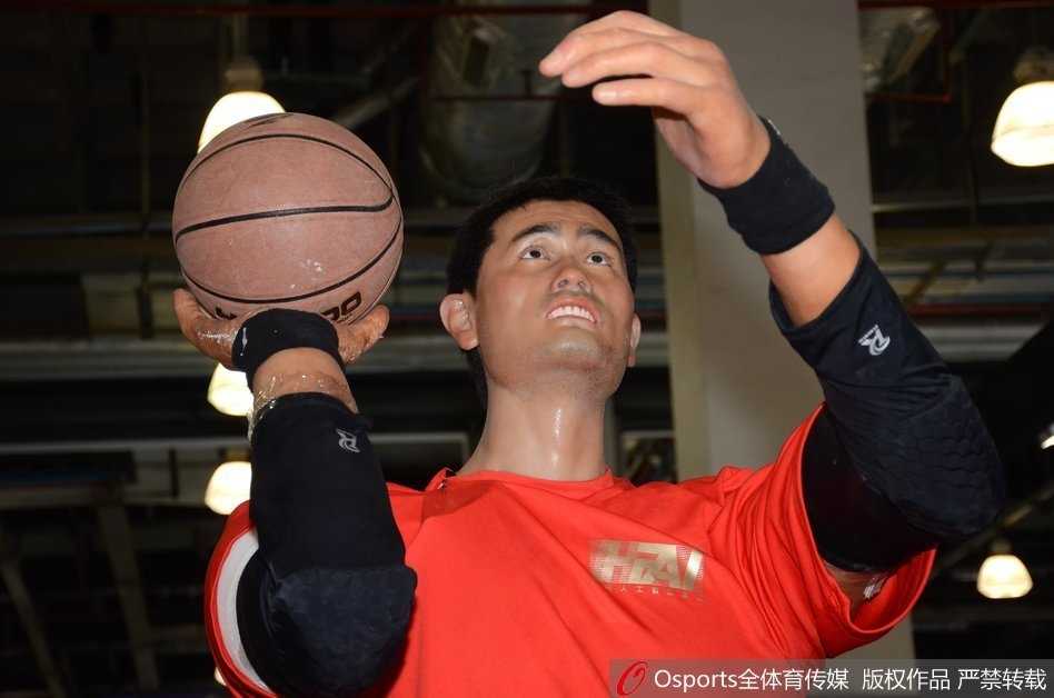 工作人员正将手中的篮球递向机器人的右手，它保持着永恒的投篮预备姿势，人与机器的互动瞬间，充满了科技传承的温度。