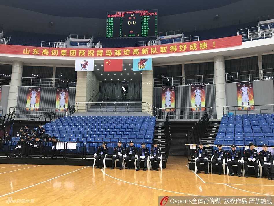 比赛当晚，青岛国信体育馆外围广场上，大批得知比赛取消的球迷神情茫然地聚集在一起，有的低头看着手机确认消息，有的正在与同伴议论，背景是体育馆亮着灯光的外立面。