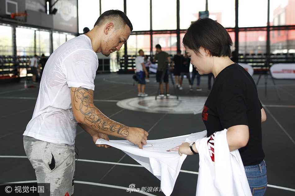 UFC名将李景亮在篮球场上持球进攻，面对防守球员，他眼神专注而犀利，尽管是跨界到篮球场，他依然保持着在八角笼中特有的沉稳与狠劲，准备完成一次上篮。