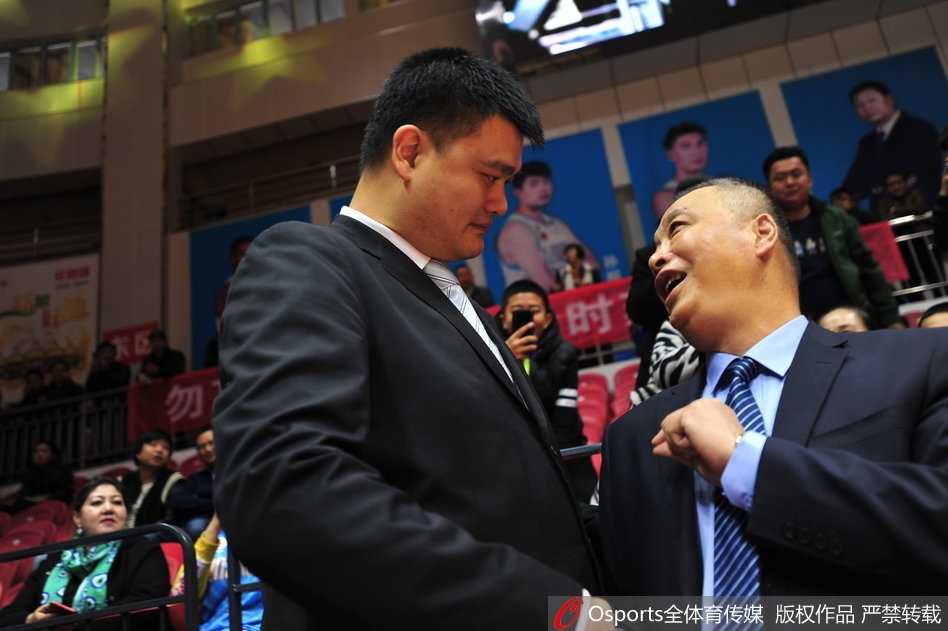 时光荏苒情谊未改:姚明与兰德里赛场叙旧 姚明和兰德里并排站在一起,两人都穿着正装,姚明双手交叉在前,兰德里则双手背后,他们面对镜头,神情轻松愉快,如同老友聚会。