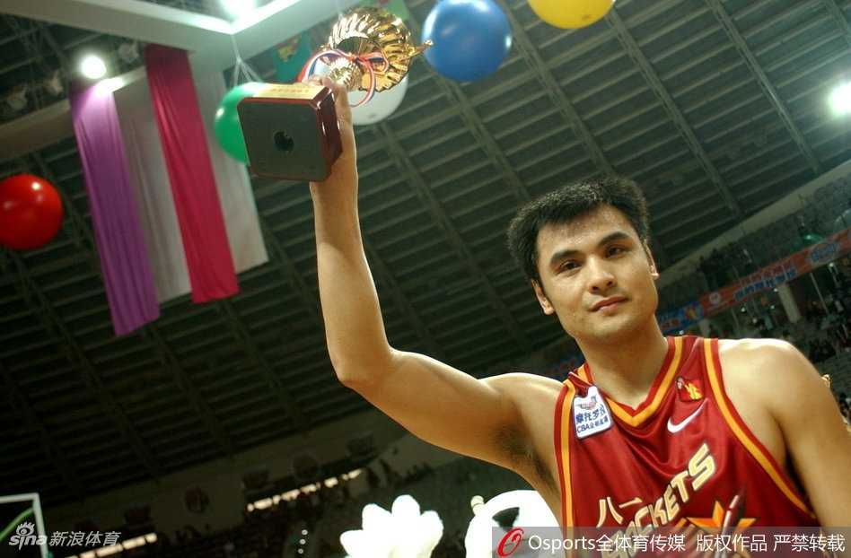 中国篮坛传奇中锋王治郅，身披战袍在对手严密防守下勾手投篮，眼神坚毅，尽显篮下霸主风范。