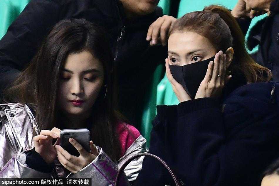 比赛暂停间隙，李旭望向场内正在聆听战术的李晓旭，两人的目光似乎隔着人海交汇，传递着无需言语的默契与支持。