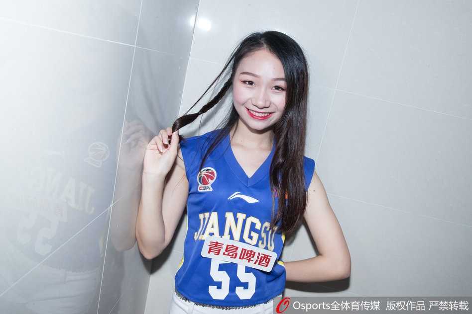 写真中，一位KDancer成员坐在更衣室的储物柜旁，单手托腮，眼神温柔而坚定，修长的身形在暖黄色的灯光下勾勒出迷人的轮廓，美得如同一幅油画。