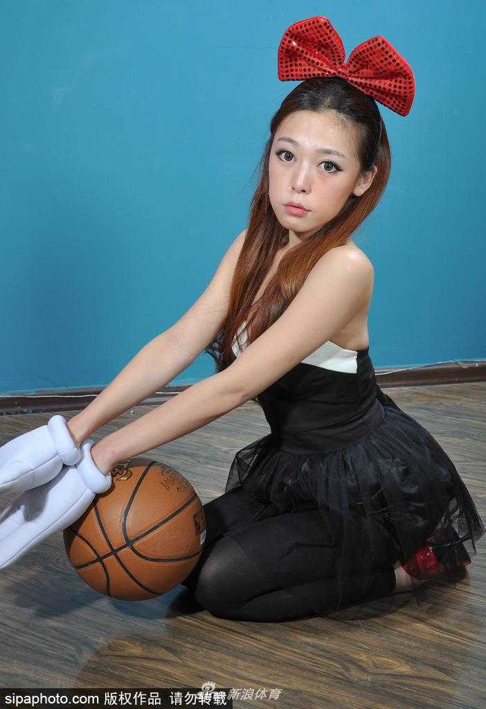 在舞台灯光的照耀下，一位宝贝手拿闪亮的花球，摆出一个可爱的思考者姿势，头上的蝴蝶结也随之轻轻晃动，显得既专业又充满少女情怀。