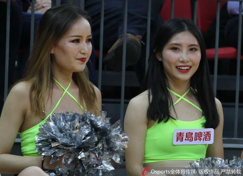 在赛场璀璨的灯光下，两位篮球宝贝背靠背摆出动感造型，修长的身姿与篮球场地板上的倒影相映成趣