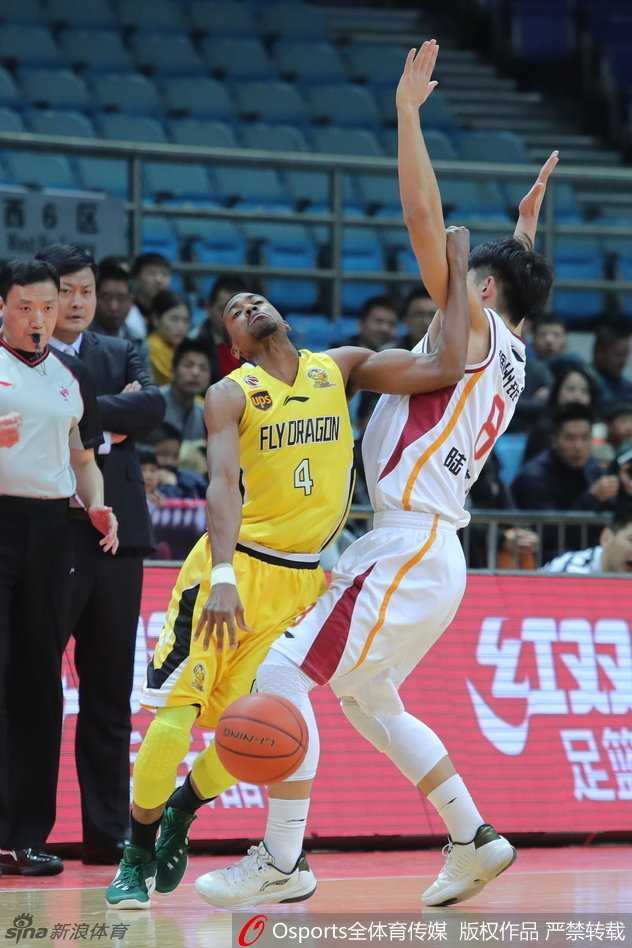 北控队外援兰多夫在高位持球观察队友跑位，他眼神犀利，利用身体优势护住球，随时准备传给空切的队友。