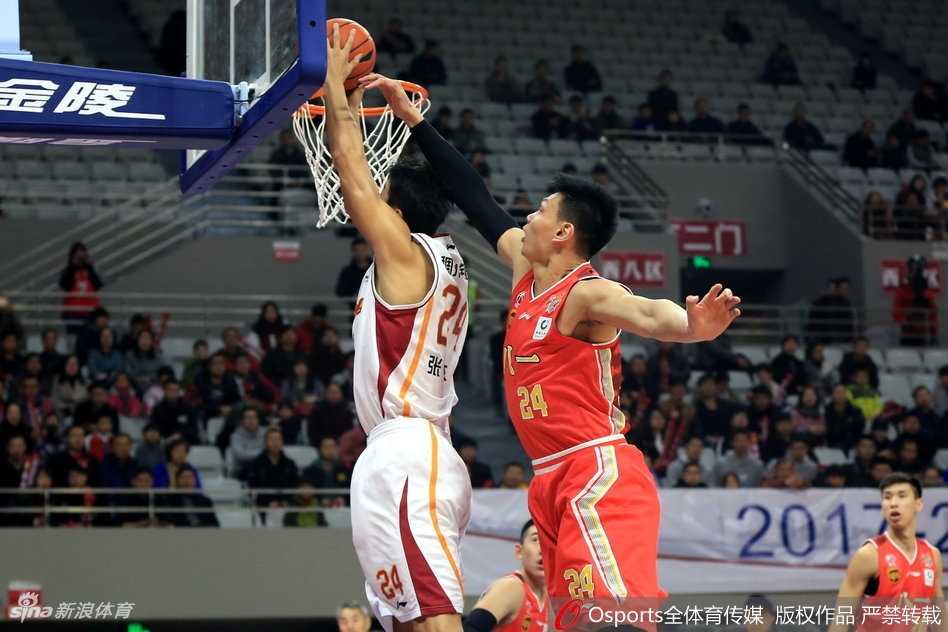 八一队球员雷蒙在失去平衡的情况下强行上篮，尽管面前是浙江队长臂的干扰，他依然顽强地将球抛向篮筐，展现了军旅球队不屈的斗志。