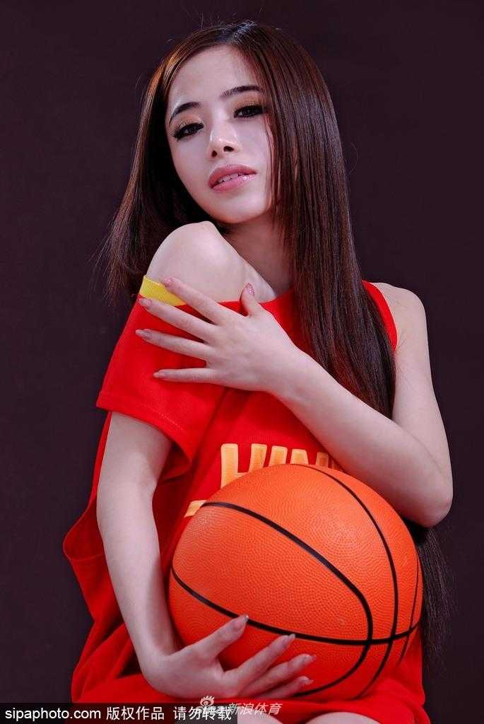 混血美女袁颖芬侧身回眸，秀发轻挽于耳后，小露香肩的弧度在光影交错中显得格外柔美，眼神中透露出对篮球赛事的坚定期许。