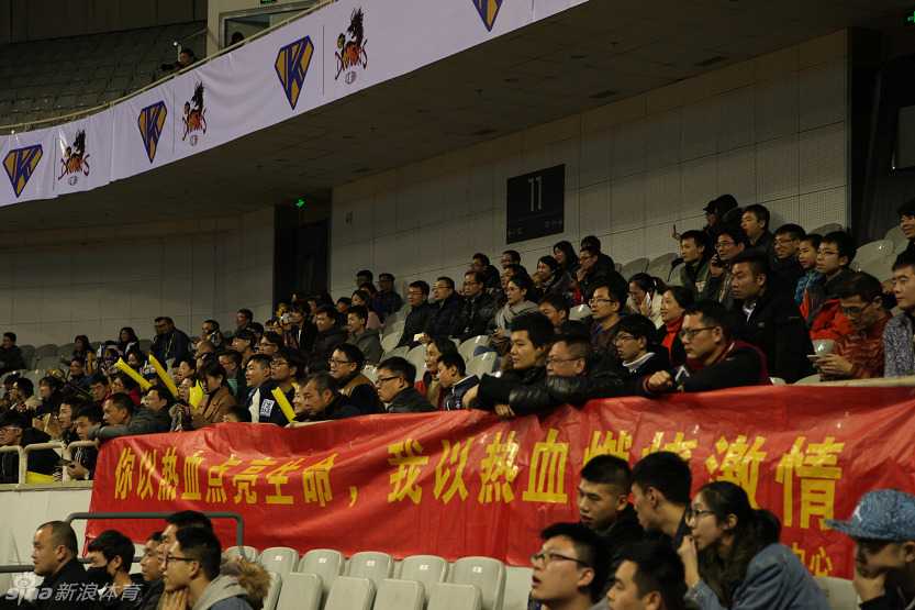 热血汇聚五台山,爱心温暖小轩轩 江苏肯帝亚队的主教练兼球员胡雪峰在场边接受媒体采访,他手持话筒,眼神坚定,身后是情绪高涨的球迷看台。