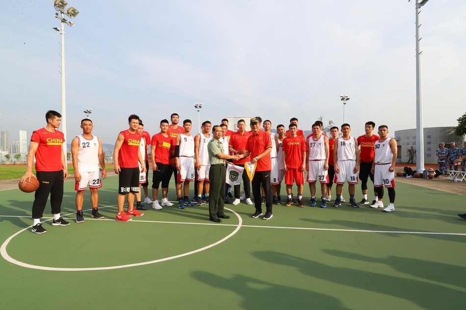 主教练李楠面带微笑，郑重地将一个签满国家队队员名字的篮球赠送给驻港部队代表，这个篮球承载着体育健儿对人民子弟兵的崇高敬意与深厚情谊。